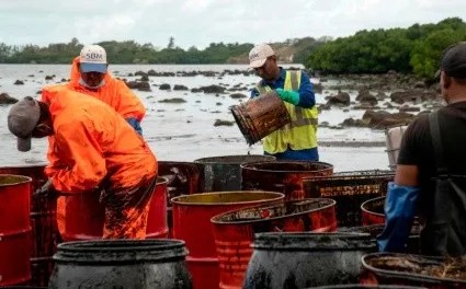 Trabajadores recogen el petrleo derramado en la playa de Riviere des Creoles.